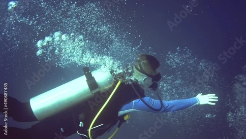 person reaches for the coral with his hand and releases oxygen bubbles.Maldives