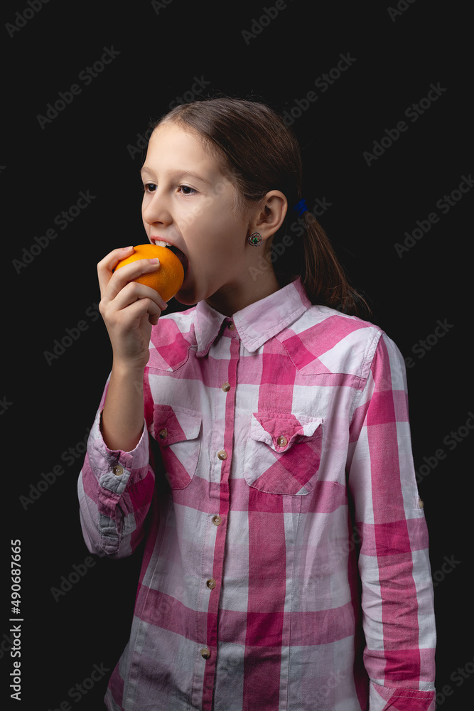 Little cute girl with tangerine posing in the studio on a black background. Little cute girl with tangerine posing in the studio on a black background.
