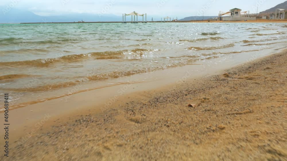 Walking to water on sandy beach, sunny day - Dead sea resort in Ein Bokek, Israel Walking to water on sandy beach, sunny day - Dead sea resort in Ein Bokek, Israel