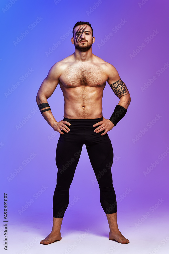 Animal instinct fitness instructor sportsman showing his incredible flexibility with an animal flow move in studio against a pink blue gradient background