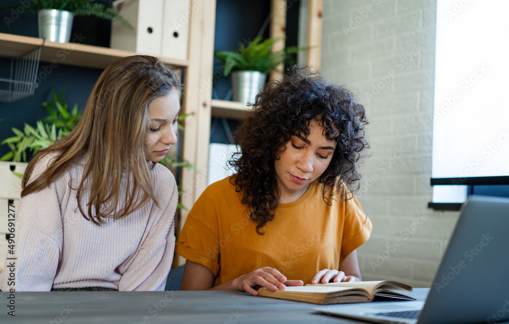 Happy multiethnic teenage friends studying in library, enjoying time together. Happy multiethnic teenage friends studying in library, enjoying time together.