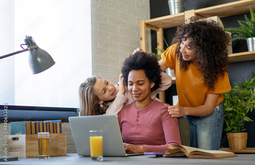 Black mother using computer and trying to focus on work while her teenager children disturb her Black mother using computer and trying to focus on work while her teenager children disturb her
