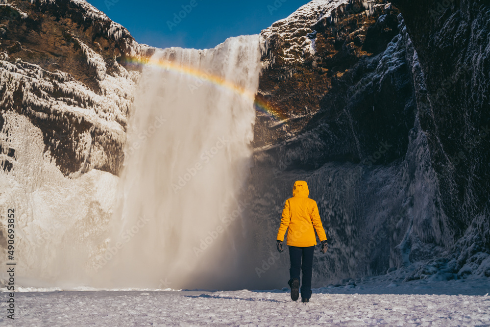 Spanish woman with yellow coat at skogafoss waterfall