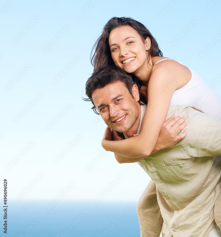 Taking her to see the view. A young man piggybacking his girlfriend with a view of the ocean in the background. Taking her to see the view. A young man piggybacking his girlfriend with a view of the ocean in the background.