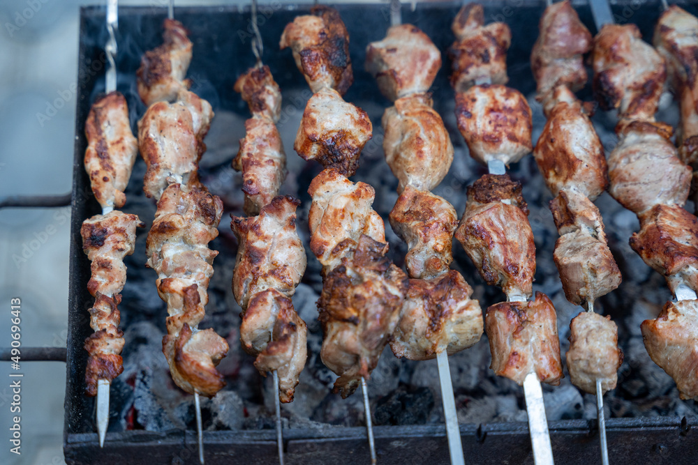 Georgian national dish meat on a spit, grilled on a large metal grill with hot charcoal, the meat is golden brown. Georgian national dish meat on a spit, grilled on a large metal grill with hot charcoal, the meat is golden brown.
