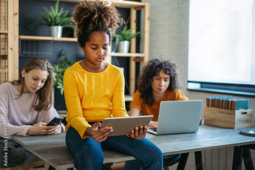 Diverse ethnicity student girls, sisters using a digital gadgets, having fun or studying together. Diverse ethnicity student girls, sisters using a digital gadgets, having fun or studying together.