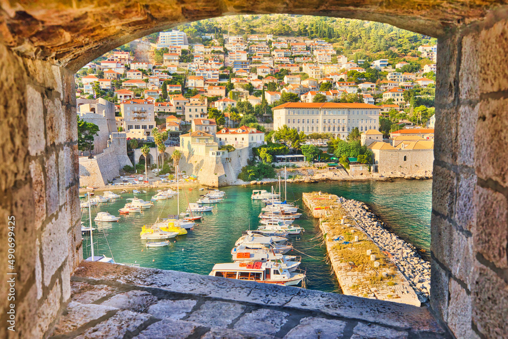 window view from Dubrovnik city walls of harbour of Dubrovnik city in Croatia. Dubrovnik historic city of Croatia in Dalmatia. UNESCO Venetian architecture. Fort Lovrijenac fortress on background. - obrazy, fototapety, plakaty 