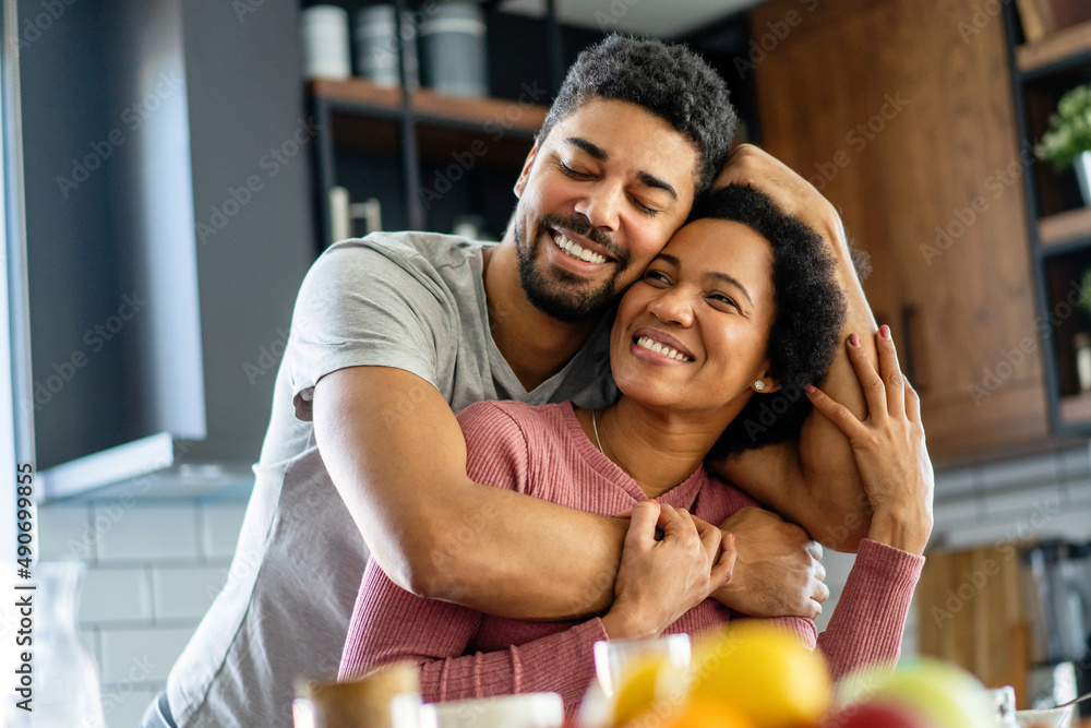 Happy young black couple have fun in modern kitchen while preparing fresh food