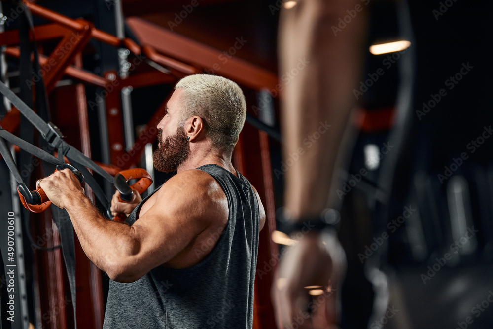 A man trains his arms and chest in the gym on the simulator, does exercises for different muscle groups. Fintes motivation, sports lifestyle, health, athletic body, body positive. Film grain. A man trains his arms and chest in the gym on the simulator, does exercises for different muscle groups. Fintes motivation, sports lifestyle, health, athletic body, body positive. Film grain.