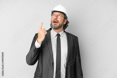 Young architect man with helmet over isolated background pointing up and surprised © luismolinero