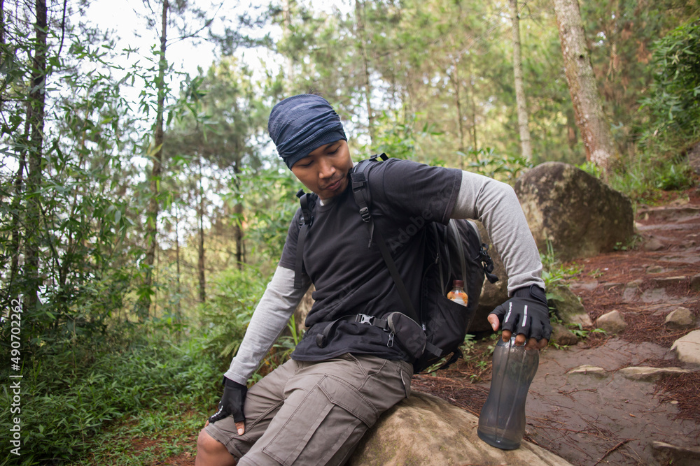Hiking man relaxing and drinking water from bottle after trekking in the mountains
Hiking man relaxing and drinking water from bottle after trekking in the mountains