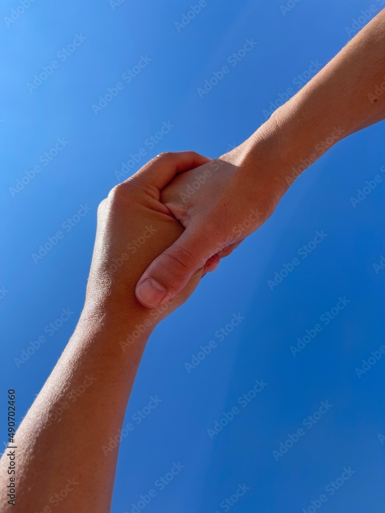 two women holding hands with blue sky background two women holding hands with blue sky background