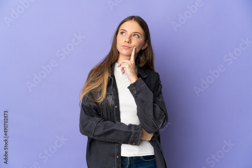 Young Lithuanian woman isolated on purple background having doubts while looking up