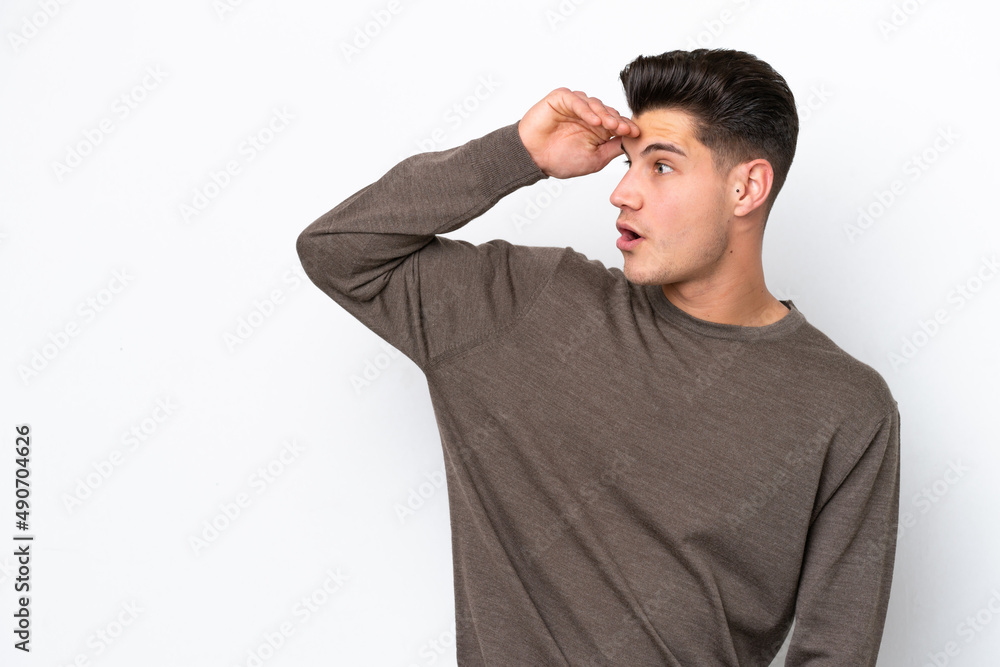 Young handsome caucasian man isolated on white bakcground with surprise expression while looking side Young handsome caucasian man isolated on white bakcground with surprise expression while looking side