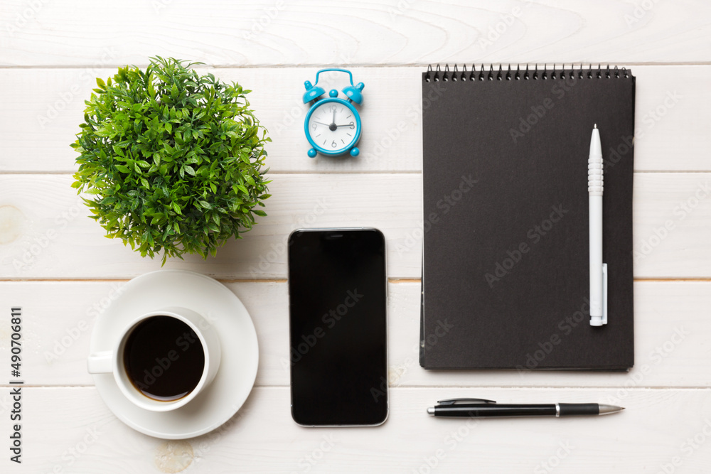 Modern office desk table with notebook, smartphone and other supplies with cup of coffee. Blank notebook page for you design. Top view, flat lay Modern office desk table with notebook, smartphone and other supplies with cup of coffee. Blank notebook page for you design. Top view, flat lay