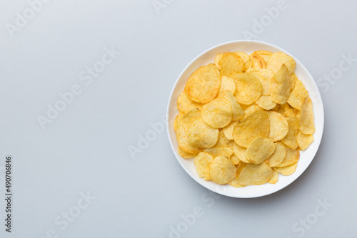 Potato chips on bowl isolated on colored background. Delicious crispy potato chips in bowl. Space for text. Top view