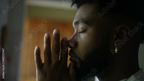 Contemplative young man praying to God An African America person prays