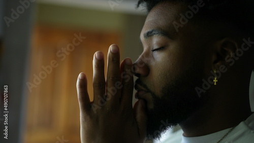 Contemplative young man praying to God An African America person prays