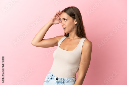 Young woman over isolated pink background with surprise expression while looking side