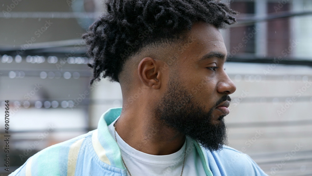 A pensive black man standing in drizzle thinking profile of young person A pensive black man standing in drizzle thinking profile of young person
