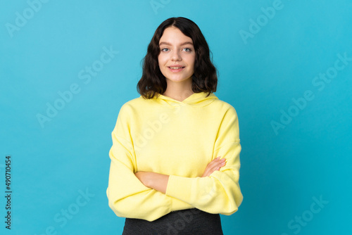 Teenager Ukrainian girl isolated on blue background keeping the arms crossed in frontal position