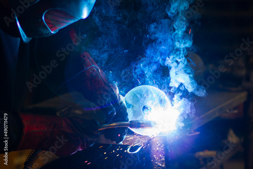 man in workshop working with metal and welding photo