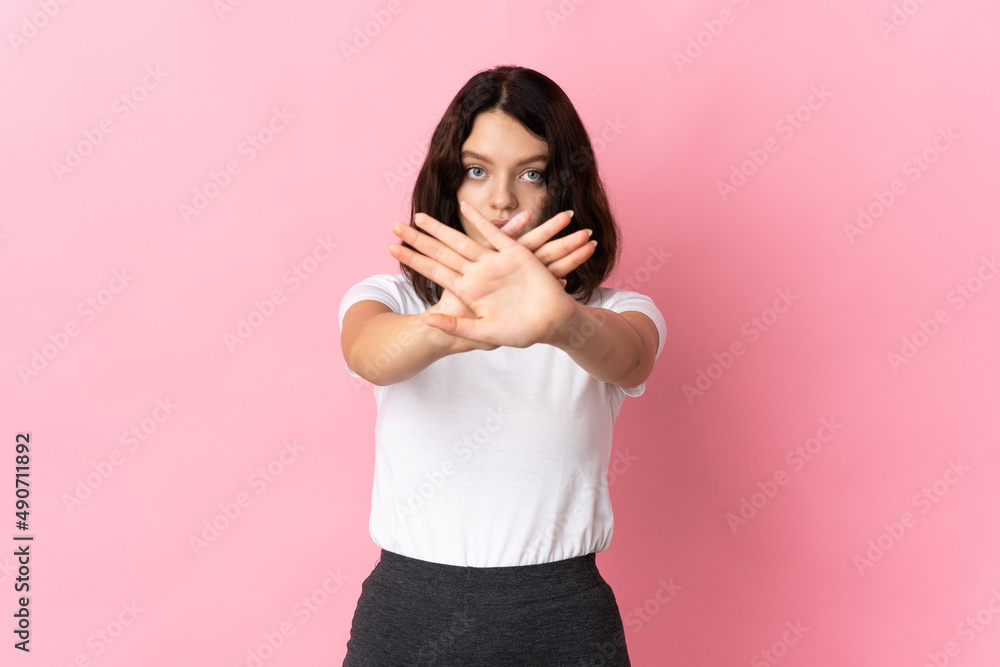 Teenager Ukrainian girl isolated on pink background making stop gesture with her hand to stop an act Teenager Ukrainian girl isolated on pink background making stop gesture with her hand to stop an act