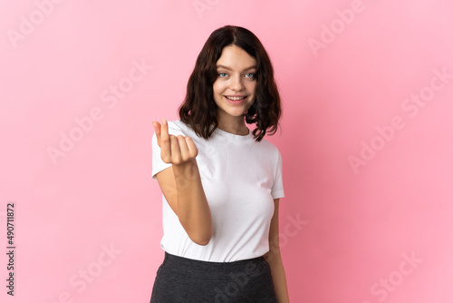 Teenager Ukrainian girl isolated on pink background making money gesture