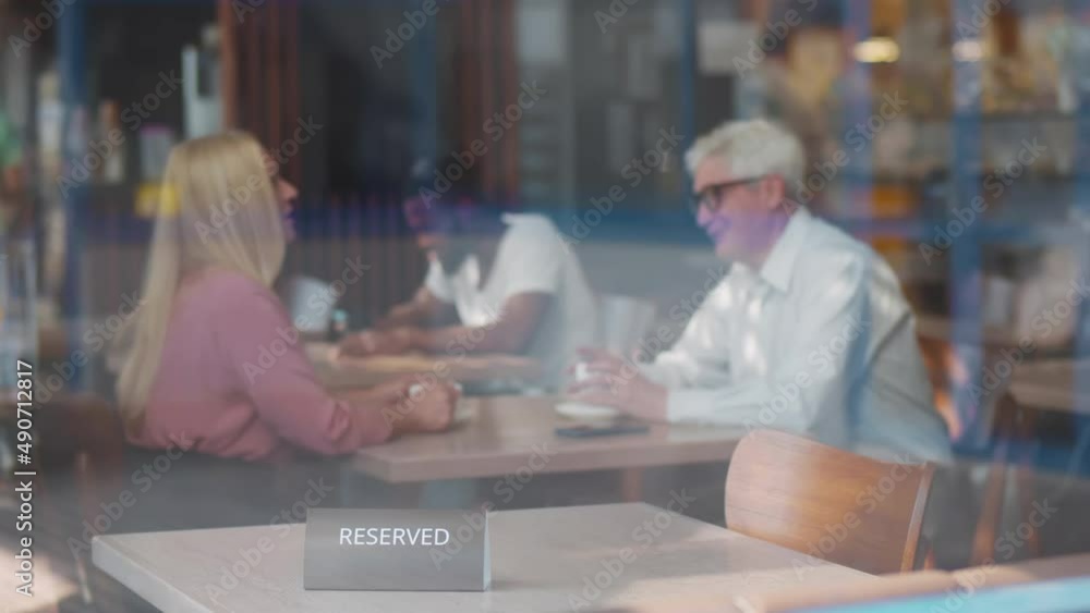 View through window of waiter put reserved sign on table in cafe. Realtime View through window of waiter put reserved sign on table in cafe. Realtime