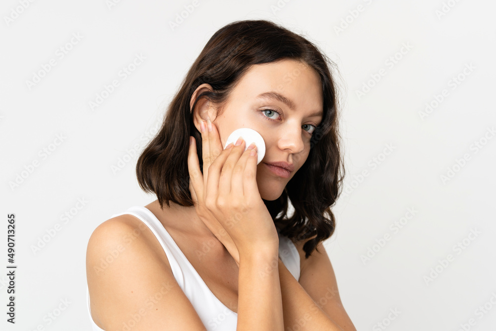 Teenager Ukrainian girl isolated on white background with cotton pad for removing makeup from her face Teenager Ukrainian girl isolated on white background with cotton pad for removing makeup from her face