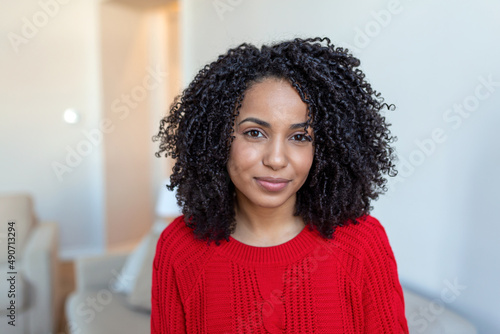 Portrait of a beautiful woman smiling at home. African woman in casual looking at camera with copy space. Cheerful mixed race girl relaxing at home with big laugh.