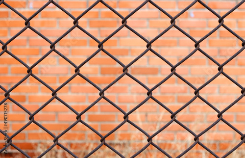 Red brick wall behind wire mesh wall.