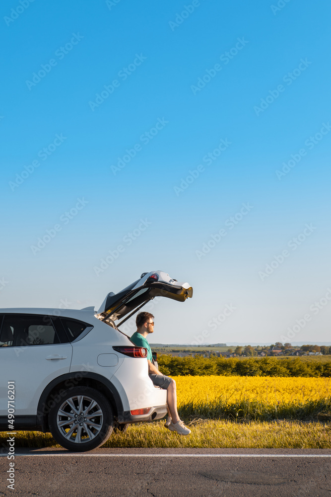 man sitting in car trunk enjoying view of sunset