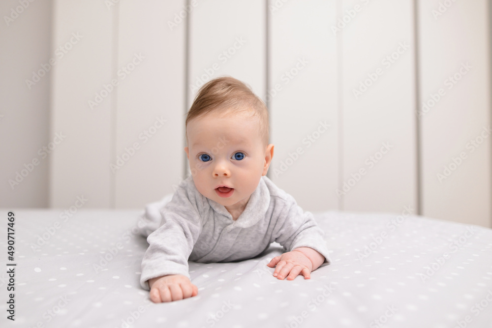 Child care Concept. Portrait of cute little baby wearing bodysuit lying on white bed sheets at home. Black infant child crawling on bed in the bedroom. Selective focus, free copy space Child care Concept. Portrait of cute little baby wearing bodysuit lying on white bed sheets at home. Black infant child crawling on bed in the bedroom. Selective focus, free copy space