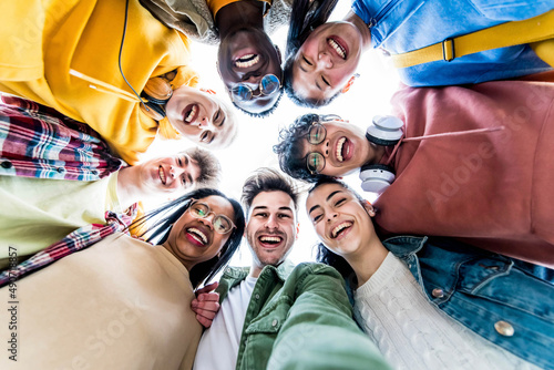 Multiracial group of young people standing in circle smiling at camera - International teamwork students hugging together - Human resources and youth culture concept photo