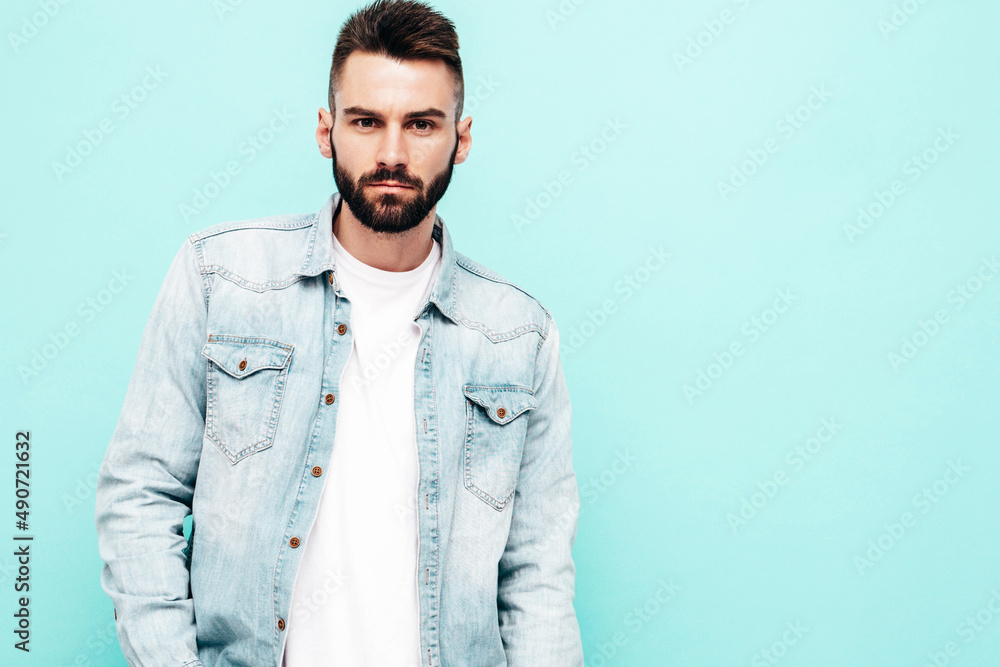 Portrait of handsome confident stylish hipster lambersexual model.Man dressed in jacket and jeans. Fashion male isolated on blue wall in studio. Thoughtful. Isolated Portrait of handsome confident stylish hipster lambersexual model.Man dressed in jacket and jeans. Fashion male isolated on blue wall in studio. Thoughtful. Isolated