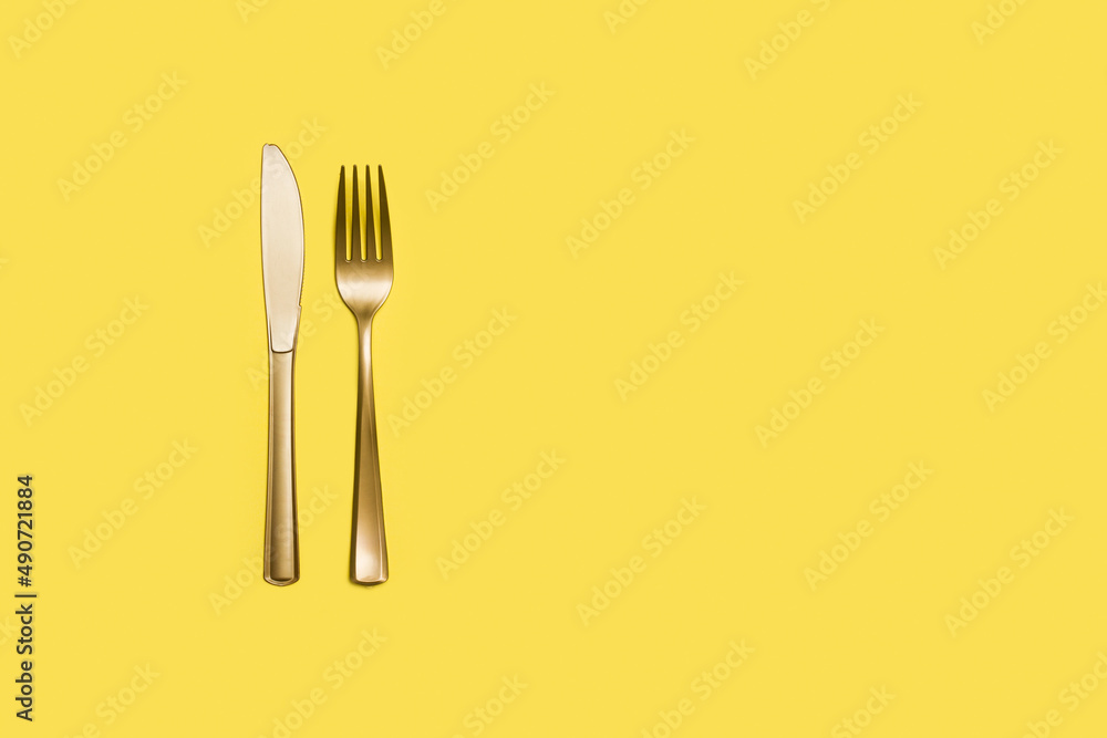 Un tenedor y un cuchillo amarillos sobre un fondo amarillo liso y aislado. Vista superior. Copy space Un tenedor y un cuchillo amarillos sobre un fondo amarillo liso y aislado. Vista superior. Copy space