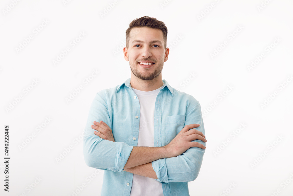 Portrait of a cheerful young man in a white T-shirt on a white background. The guy is standing looking at the camera and smiling.