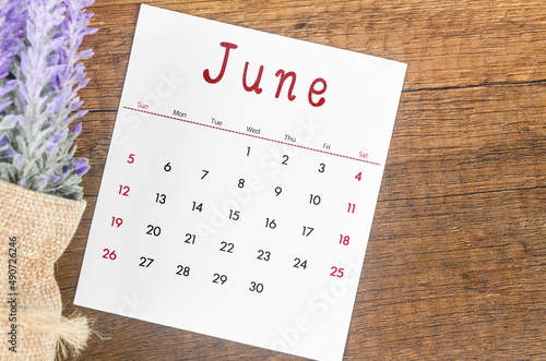 June 2022 calendar with flower on wooden background. photo