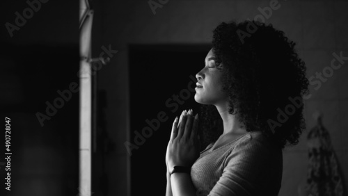 A woman praying at home by window having HOPE and FAITH in monochrome