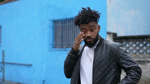 Fotografija A tired black man rubbing eye and face outside