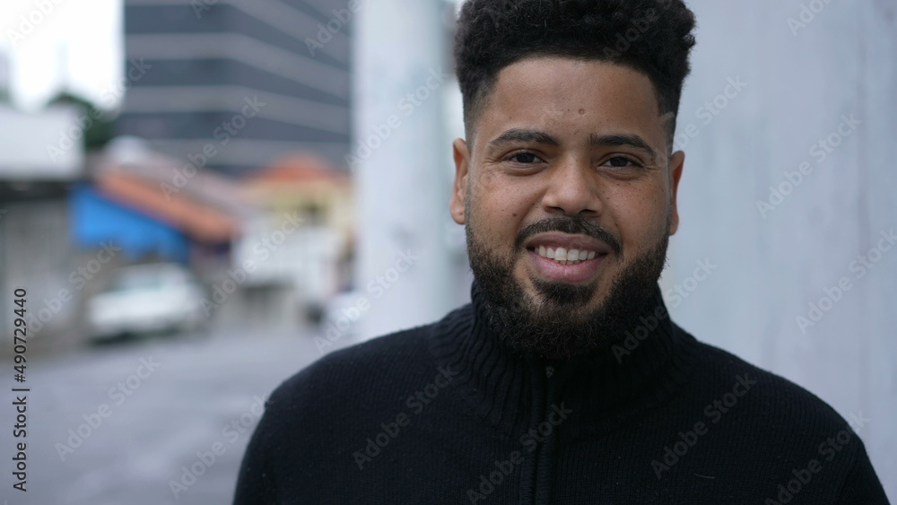 Fototapeta premium A diverse man walking forward toward camera smiling in urban sidewalk