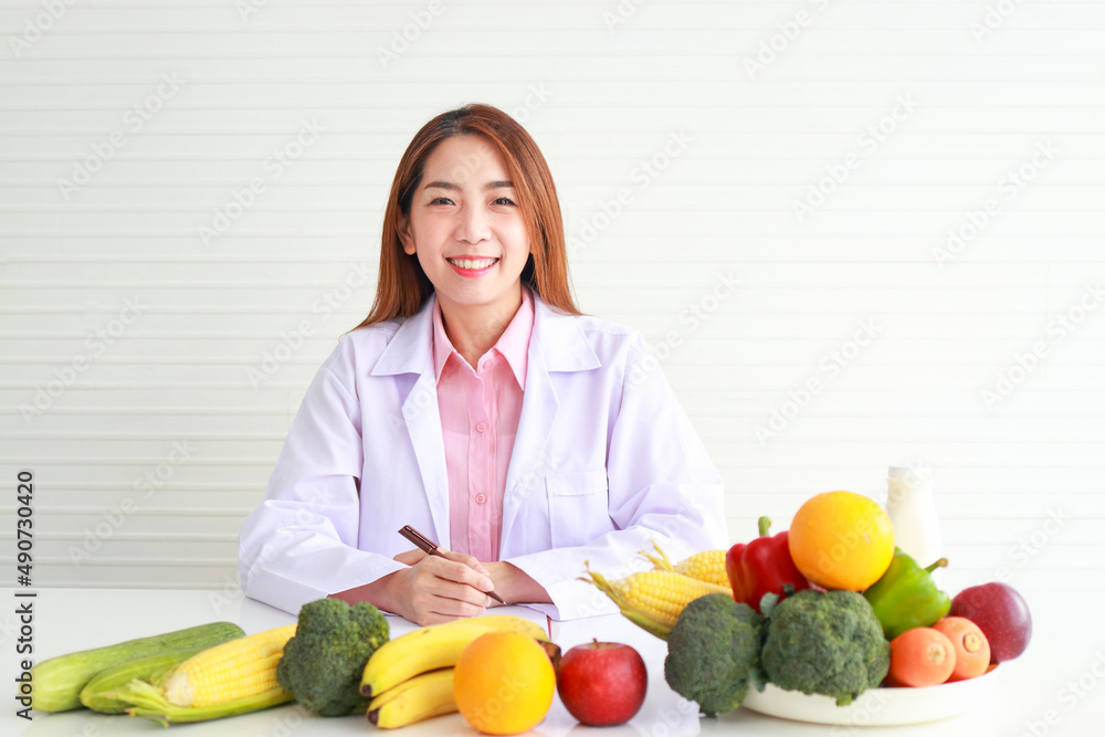 Beautiful Asian nutritionist sitting at her desk with fruits and vegetables she gave advice and prepare nutritious food Eat clean, healthy food. health care concept Beautiful Asian nutritionist sitting at her desk with fruits and vegetables she gave advice and prepare nutritious food Eat clean, healthy food. health care concept