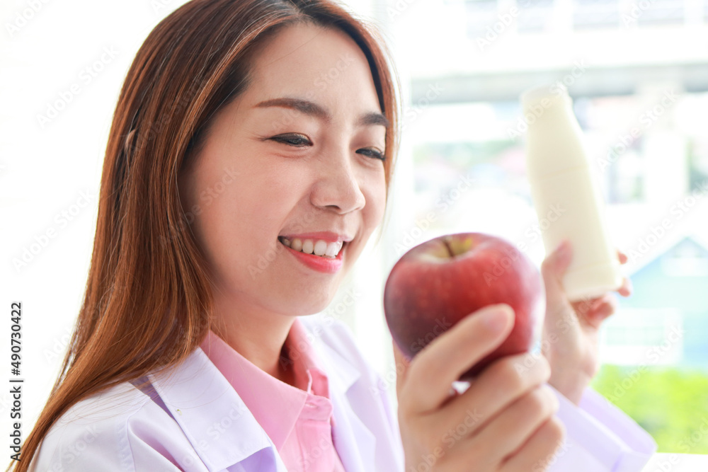 beautiful asian nutritionist She holds a milk bottle with an apple. she gave advice and prepare nutritious food Eat clean, healthy food. health care concept beautiful asian nutritionist She holds a milk bottle with an apple. she gave advice and prepare nutritious food Eat clean, healthy food. health care concept
