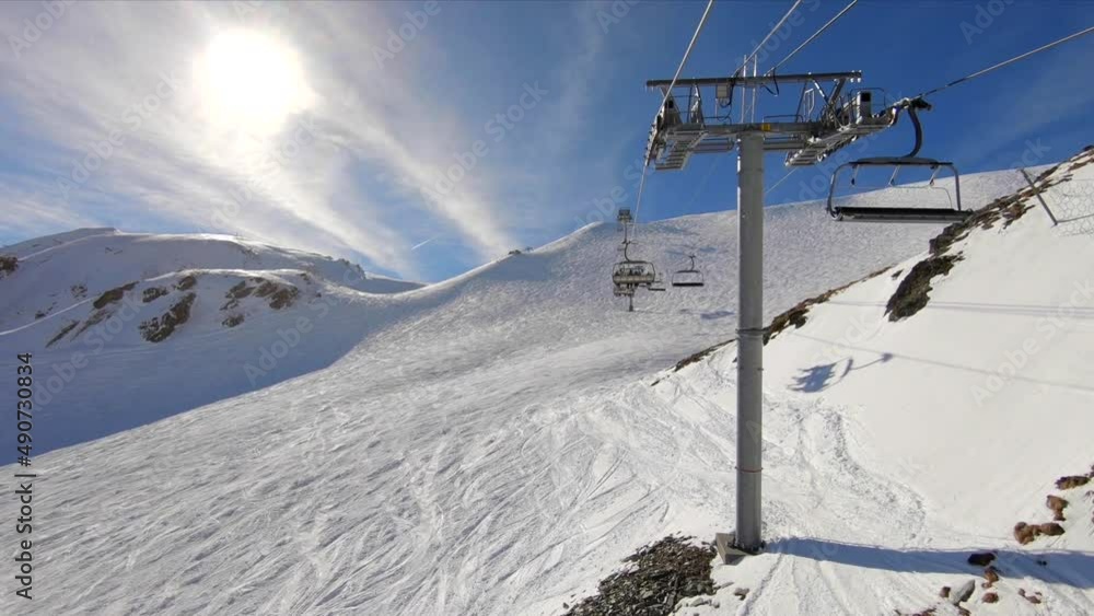 View from a skilift over a ski slope in a snowy mountain landscape, on a sunny day. View from a skilift over a ski slope in a snowy mountain landscape, on a sunny day.