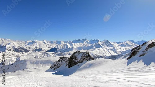 Wide droneshot of a single off-piste skier in a snowy mountain landscape in the French Alps.