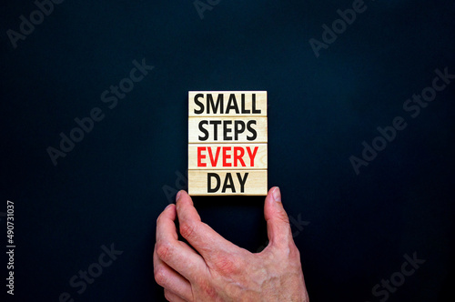 Small steps every day symbol. Concept words Small steps every day on wooden blocks. Businessman hand. Beautiful black table black background. Small steps every day business concept. Copy space.