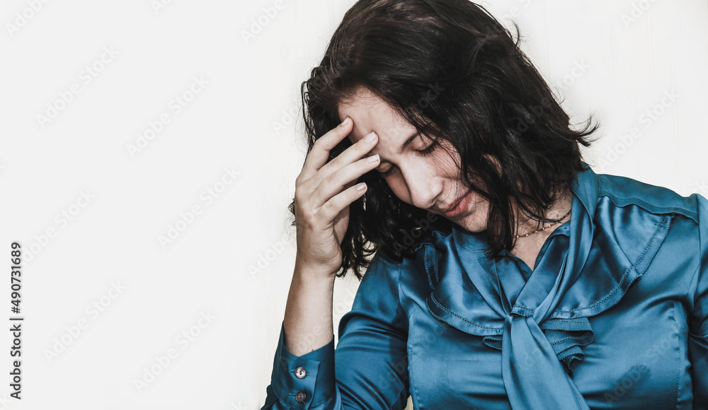Young caucasian woman expressing a tense and anxious expression holds her temple with a gloomy face
Young caucasian woman expressing a tense and anxious expression holds her temple with a gloomy face