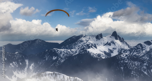 Adventure Composite Image of Paraglider Flying up high in the Rocky Mountains. Cloudy Sky. Aerial Background from British Columbia, Canada. Extreme Sport Concept. winter