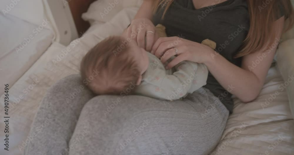 New Mum Cradling her Baby and Smiling in Bed at Home New Mum Cradling her Baby and Smiling in Bed at Home